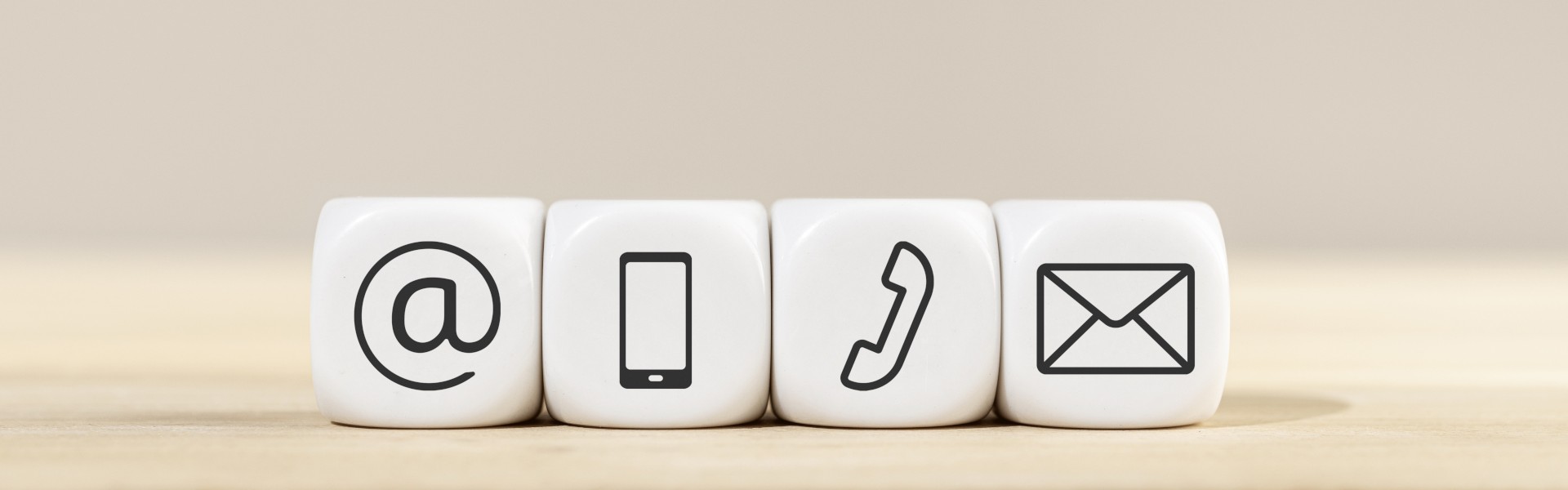 Symbole für E-Mail, Smartphone, Telefon und Briefumschlag auf weißen Würfeln.